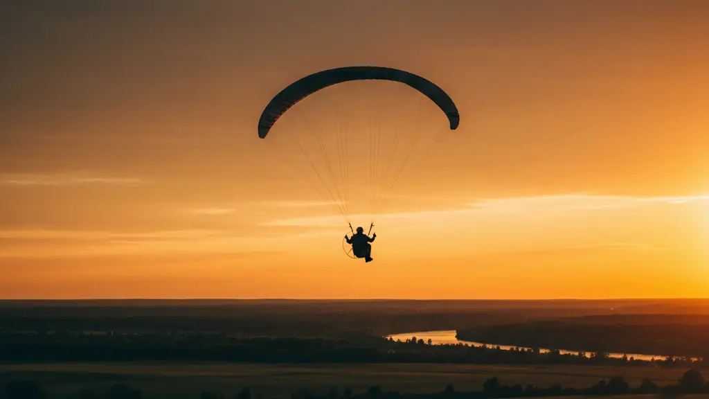 Paramoteur en vol au coucher du soleil au-dessus des champs et d'une rivière de la Mauricie